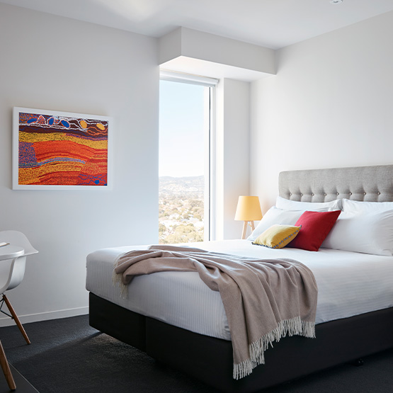 A hotel room with a Queen size bed and art on the left wall